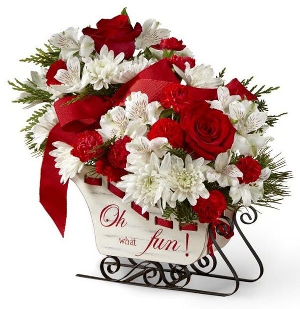 an array of red roses, carnations, and white alstroemeria in a festive wooden holiday sleigh,