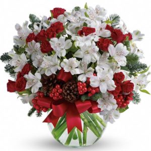delightful winter white arrangement with white alstroemeria and red carnations pine cones and holly berries