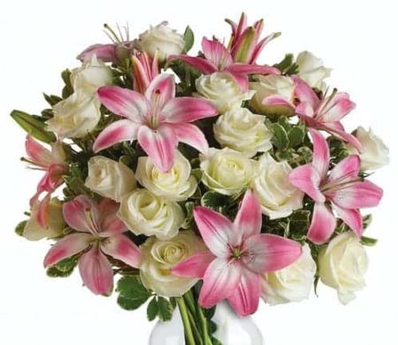 An eye-catching display of roses and lilies is perfectly arranged in a feminine vase which makes a beautiful and lasting impression.